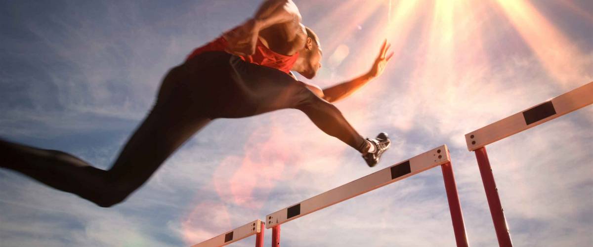 Runner jumping over running hurdle, low angle view