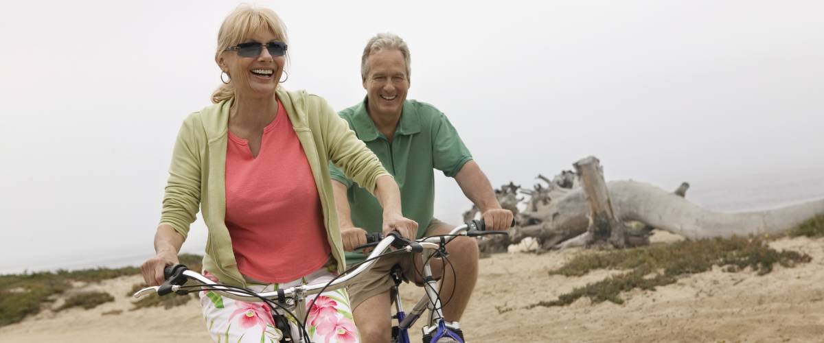 Older couple biking on the beach