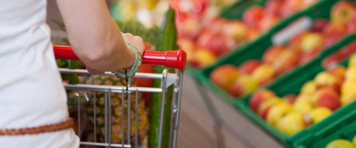 Cropped image of young woman pushing shopping cart in grocery store