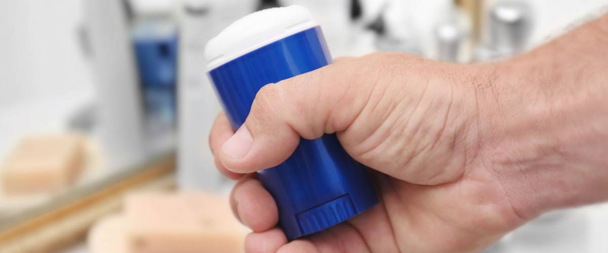 Man holding deodorant in bathroom
