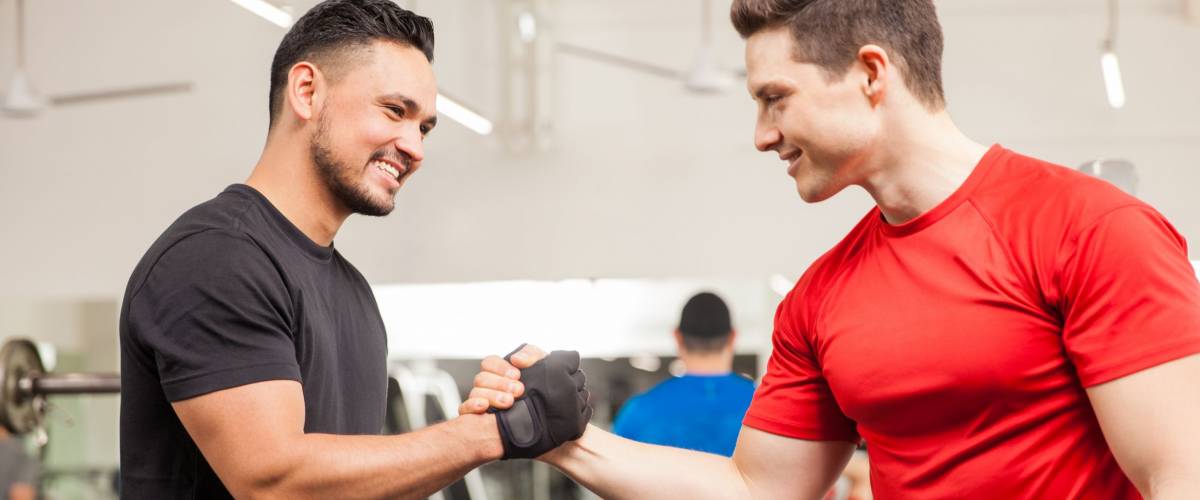 Two young men meeting at the gym and giving each other a handshake