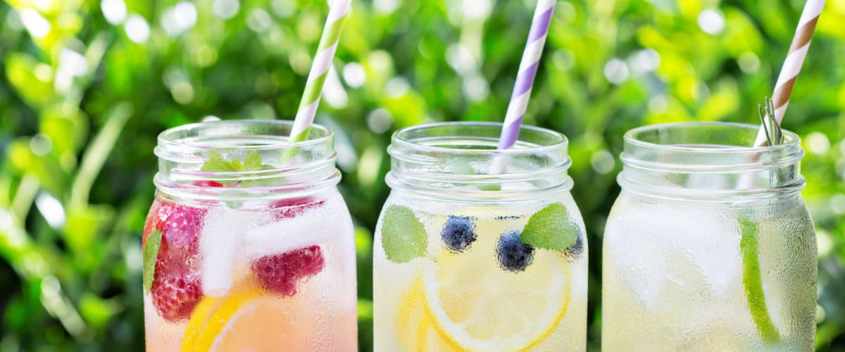 Variety of lemonade in mason jars with berries and fruits on the front porch