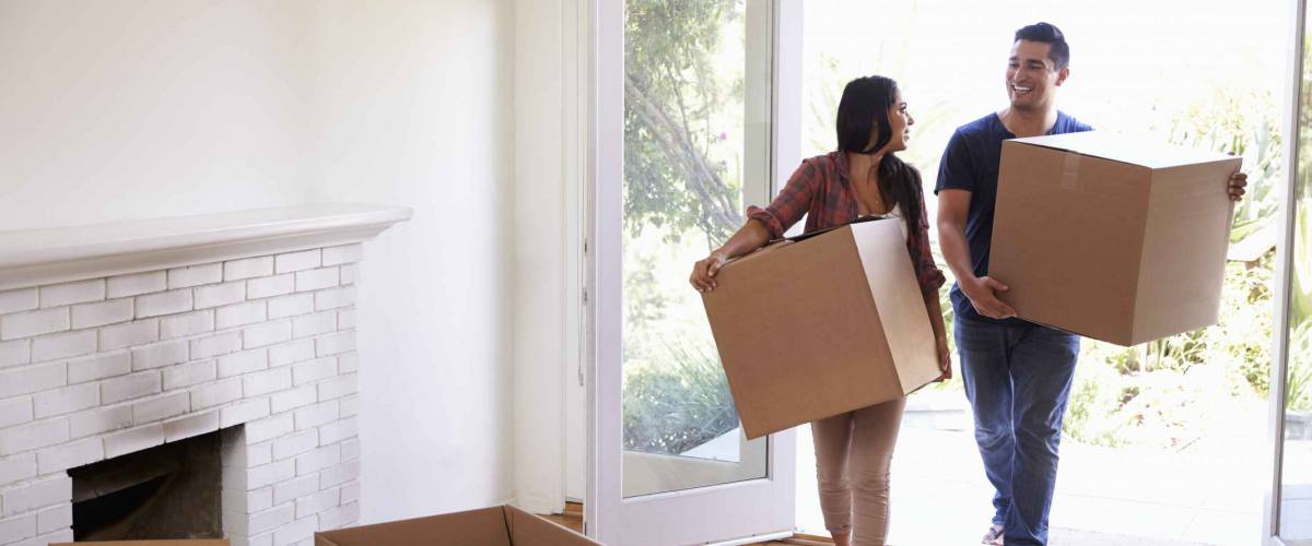 Couple Carrying Boxes Into New Home On Moving Day