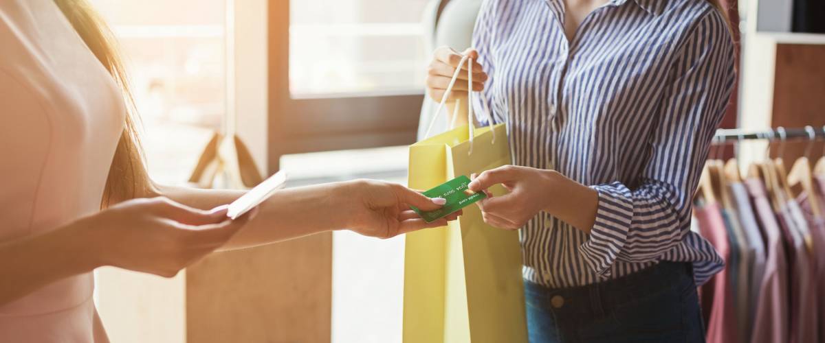 Woman paying with credit card for purchase at clothes showroom