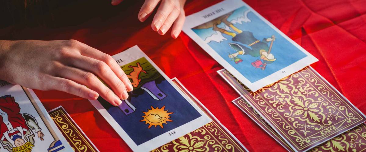 Fortune teller using tarot cards on red table