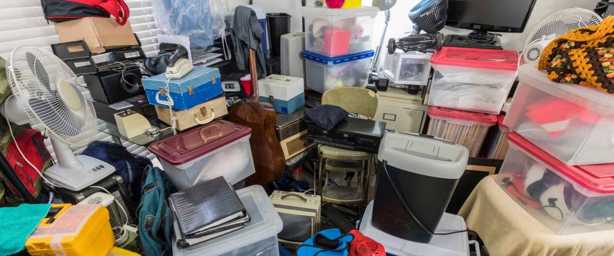 Hoarder room packed with storage boxes, old electronics, files, business equipment and household items.