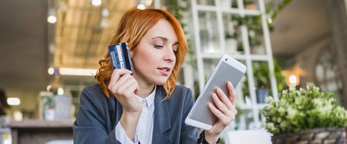 Beautiful European girl using her tablet to do internet banking, online shopping while she holding credit card in another hand. Paypal concept. Internet Banking concept. - Image
