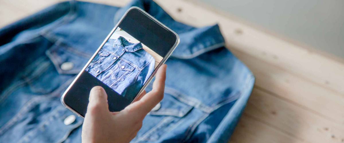 young Women taking photo to shirts with cell telephone or smartphone digital camera for Post to sell Online on the Internet .