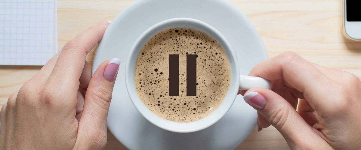 Coffee break. Female hands touches white cup of classic coffee, top view, close up. Pause icon on foam. Pause, break, short breather, relax, pit stop in the middle of business life.
