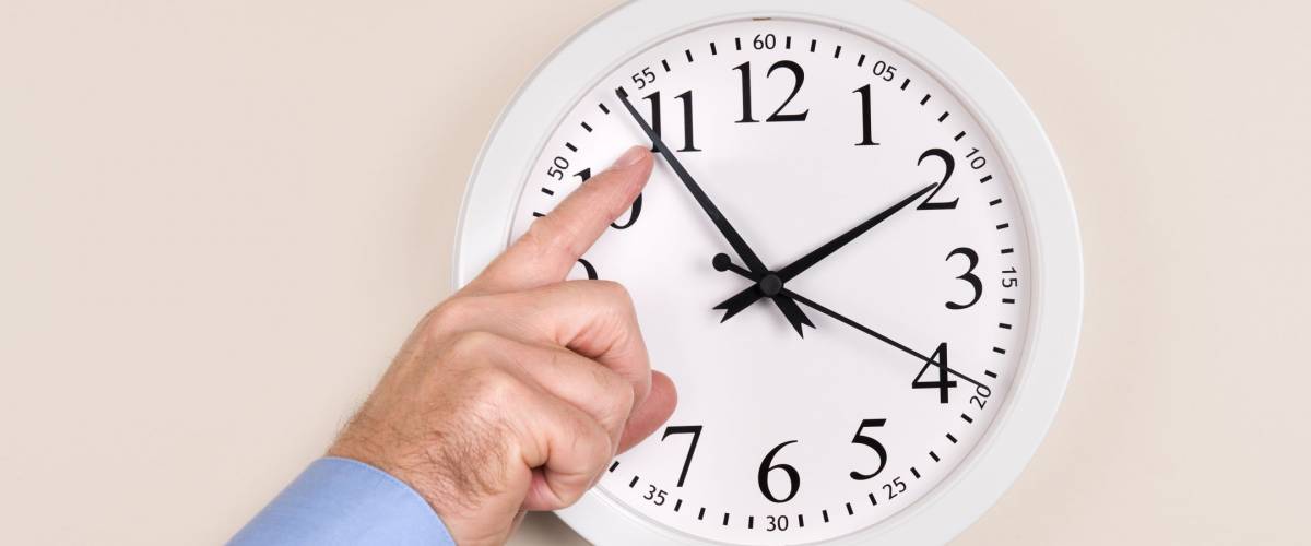 A man changes the time on a clock, moving it forward in time, spring forward.