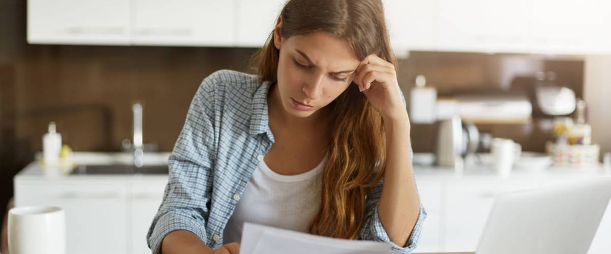 Attractive young housewife wearing shirt at home studying gas and electricity bills.