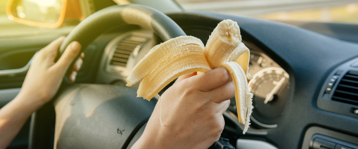 Woman eating a banana while driving a car