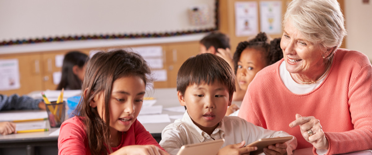 Older teacher with young elementary students in classroom