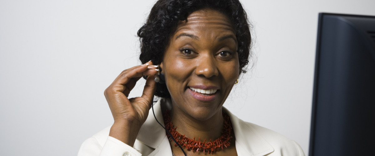 Adult middle aged woman listening to audio on headphones sitting in front of computer