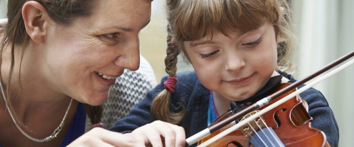 Woman tutoring a young girl on violin lessons