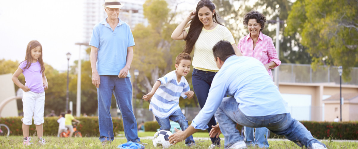 Multi-generational family playing soccer in the park