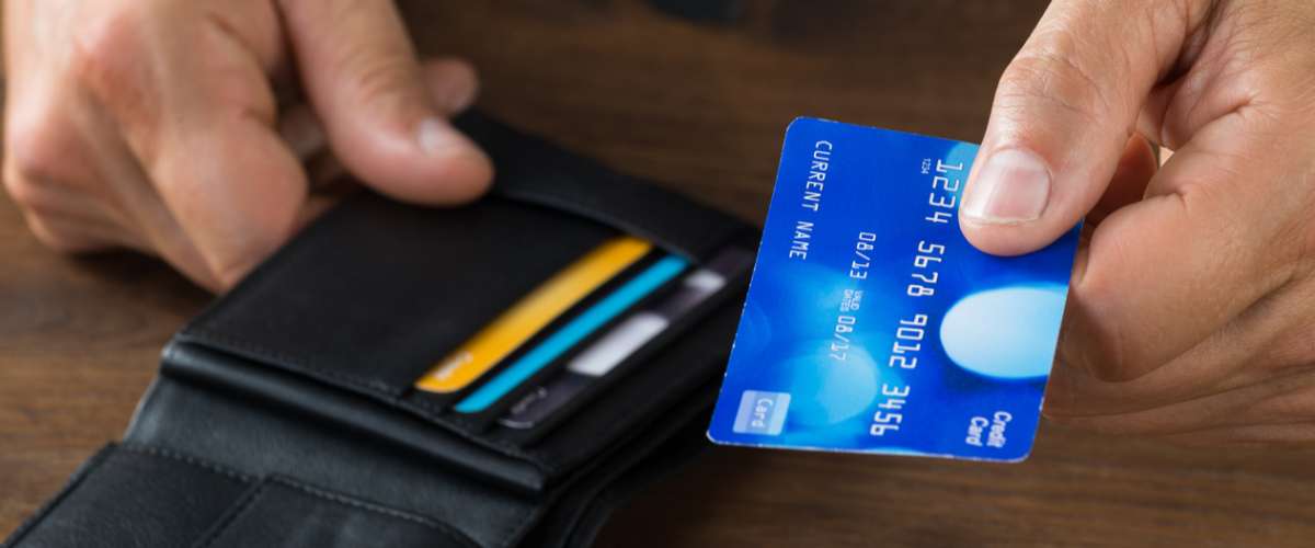 Cropped image of businessman giving credit card from wallet at desk