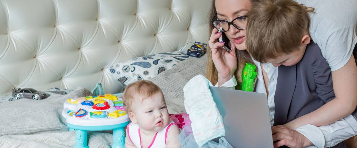 A mom is trying to work. A business woman trying to do something, mother is in stress situation and her kids are distracting and they want attention and play games. Focus is om woman face