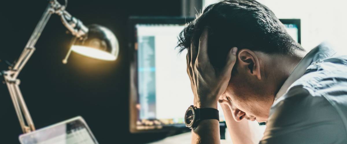 Tired and worried business man at workplace in office holding his head on hands after late night work, concept