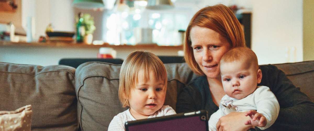 Children reading on a tablet with their mother