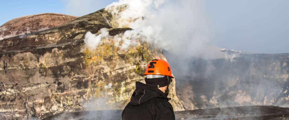 geologist looks at the craters of the erupting volcano Etna