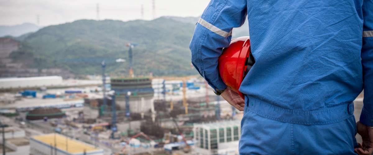 engineer in safety suit stand in front of nuclear construction