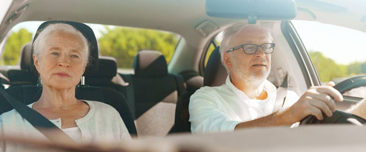 road trip, travel and old people concept - happy senior couple driving in car