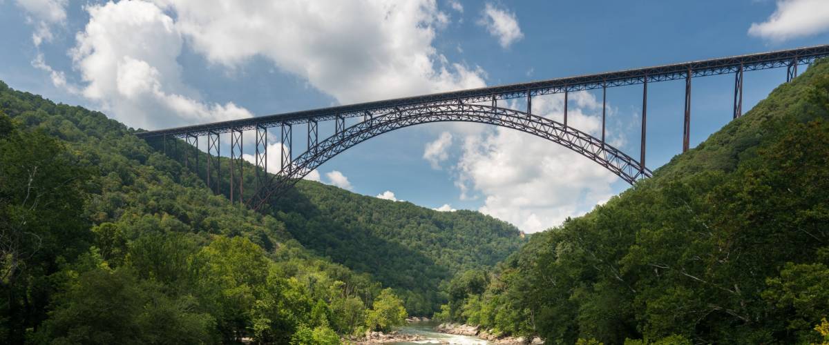 Rafters float towards the rapids under the high arched New River Gorge bridge in West Virginia