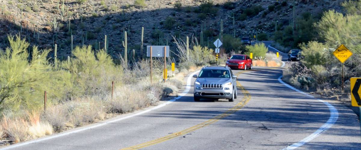 ARIZONA, USA - DECEMBER 26, 2016: Scenery of winding asphalt road with no cars between mountains. Arizona desert landscape with red rock mountains and Saguaro cacti.