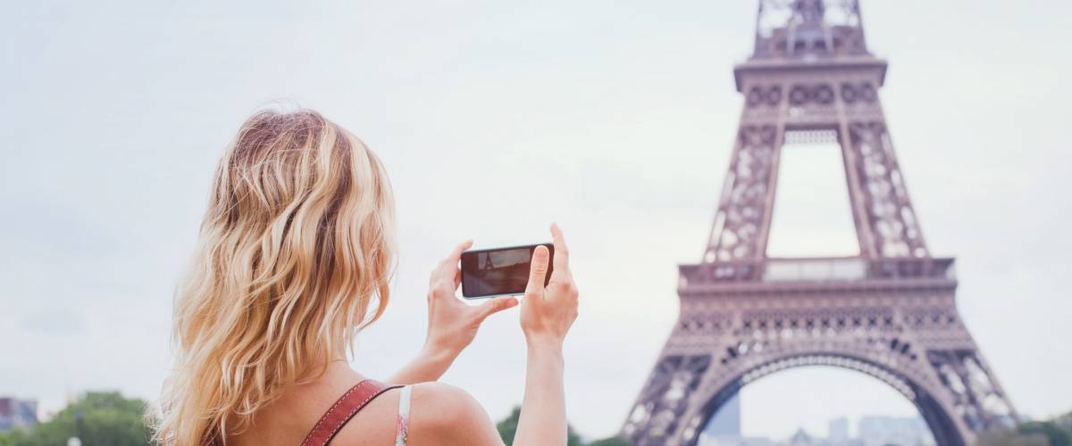 tourist taking photo of Eiffel tower in Paris with compact camera or smartphone, travel in Europe