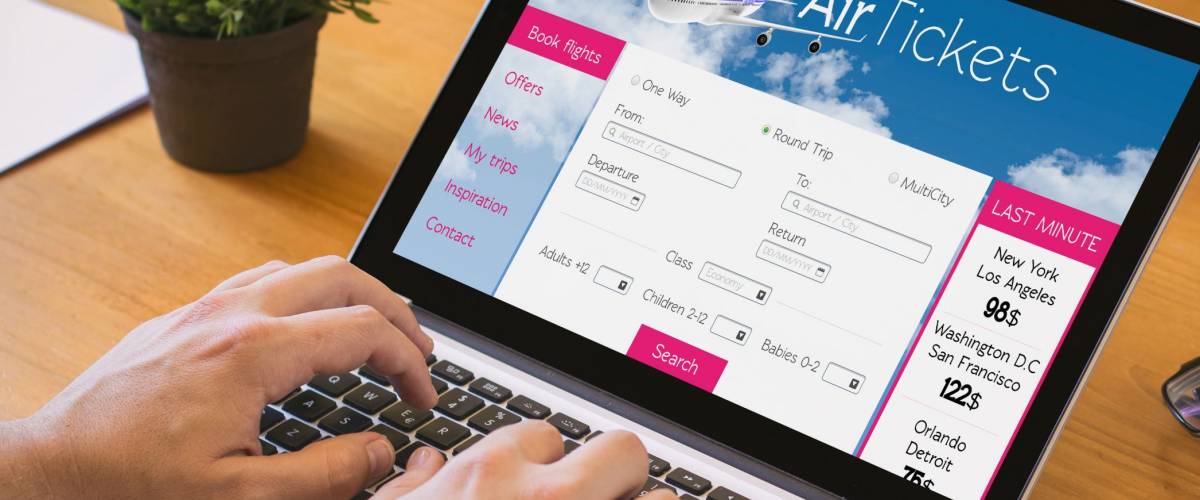 Close-up top view of man working on laptop with tickets flights web. all screen graphics are made up.
