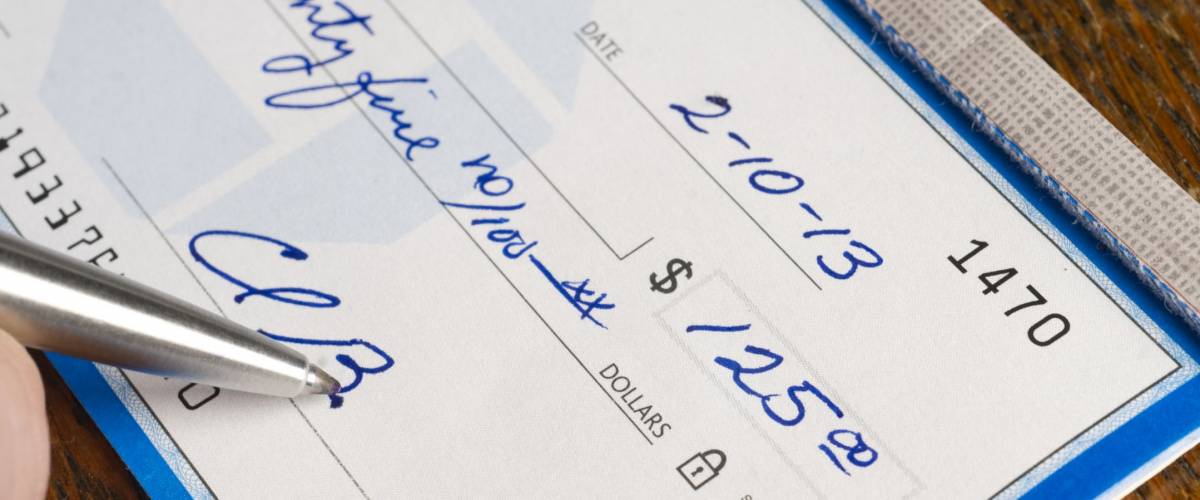 A Check is signed paying bills in ballpoint pen on the desk pay promise