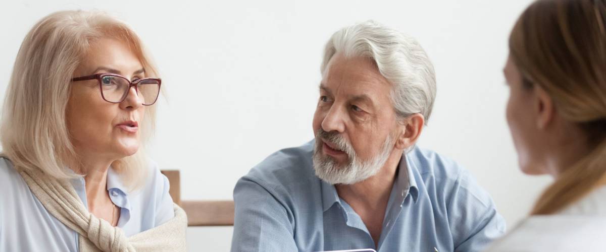 Senior couple talk to real estate agent about house purchase at meeting