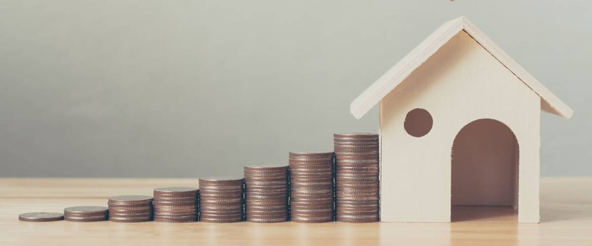 Property investment and house mortgage financial concept, Hand putting money coin stack with wooden house