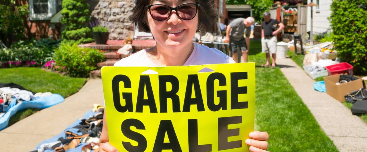 happy woman ready to sell items at yard sale.