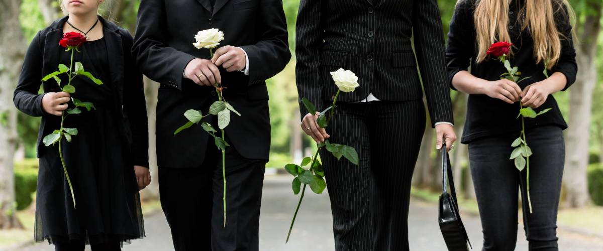 Torso of family on cemetery mourning holding red and white roses in hands