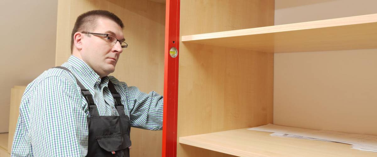 Carpenter assembling wardrobe furniture in walk-in closet