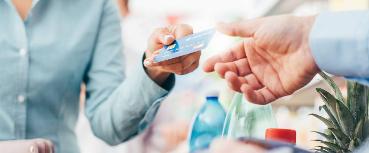 Woman at the supermarket checkout, she is paying using a credit card, shopping and retail concept