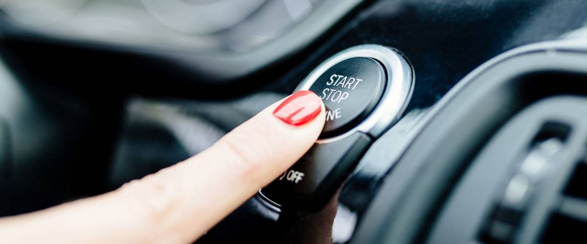 Woman starts the car engine with start-stop button. Modern car interior