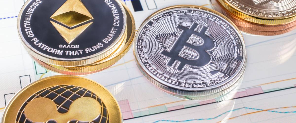 Montreal, CA - 16 April 2018: Cryptocurrency coins over tablet screen showing candlestick chart. Bitcoin, Ethereum and Ripple are the top 3 Cryptocurrencies by Market Capitalization.