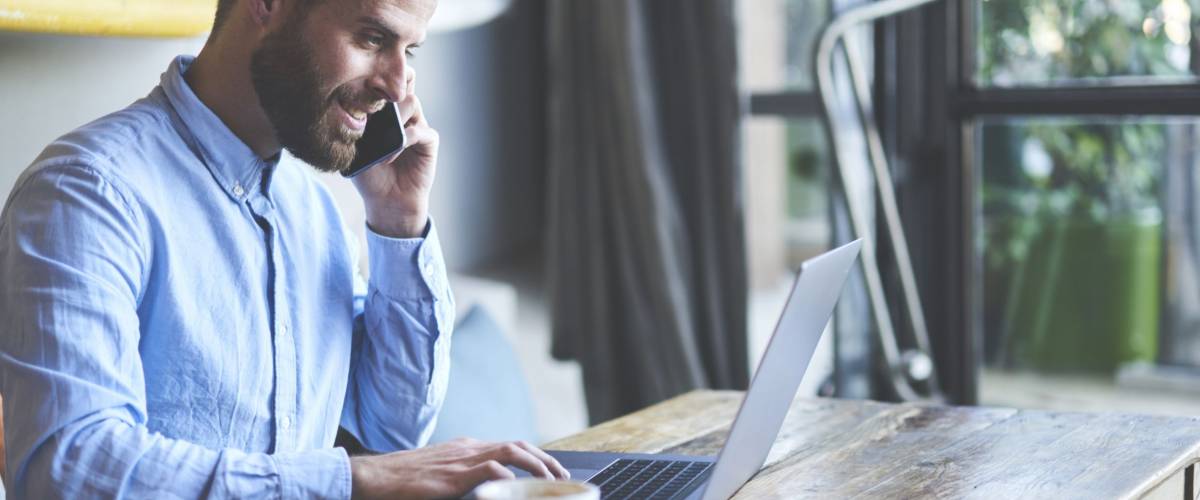 Successful male owner of business company talking with operator while making banking online