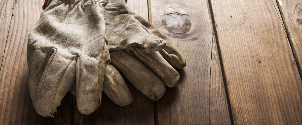 Old working gloves over wooden table, construction tools