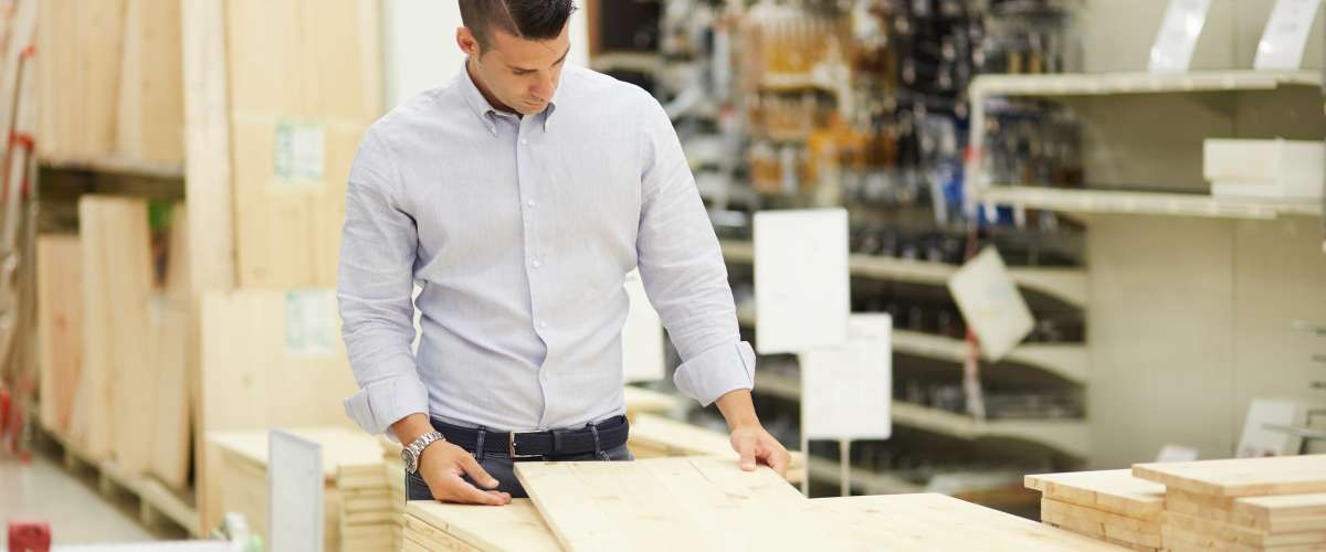 young man buying lumber in a hardware store