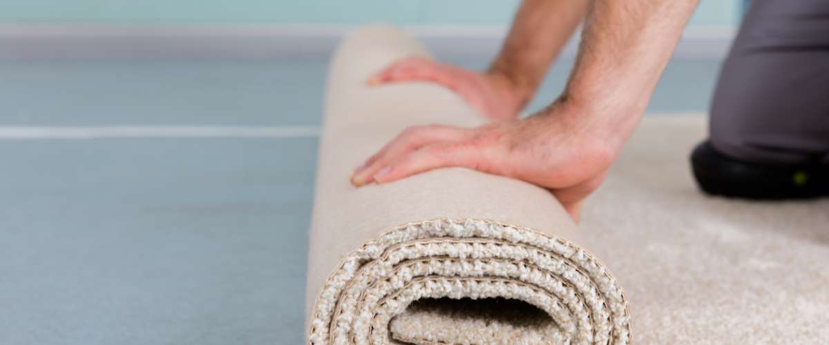 Close-up Of Worker's Hands Rolling Carpet At Home