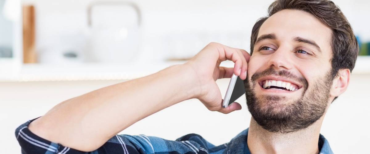 A man is talking on the phone and smiling at work