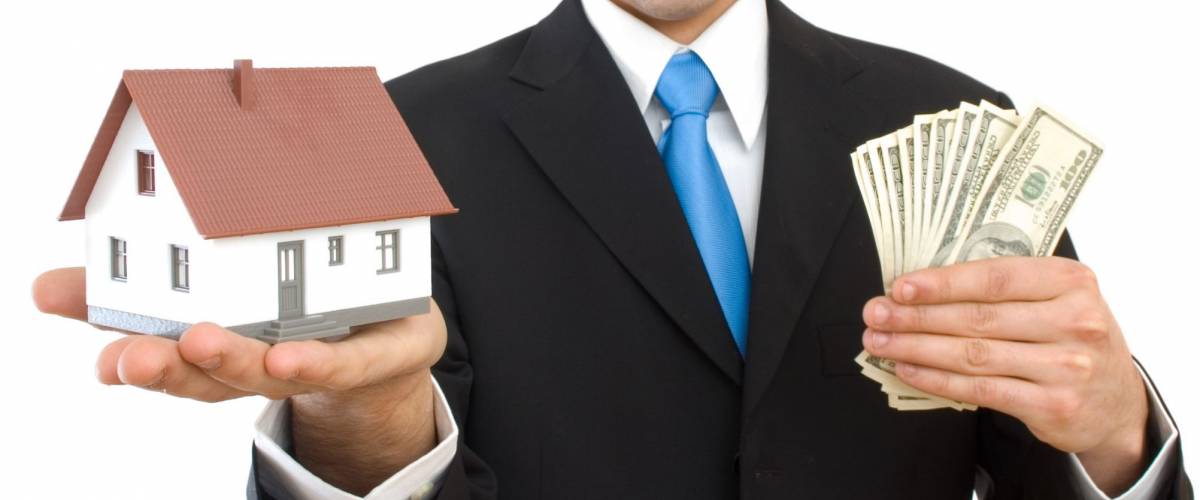 happy businessman with a house and US dollars for real estate concept