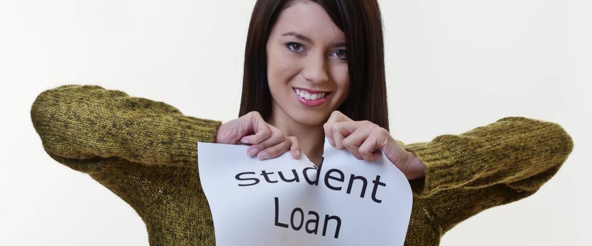 woman holding up a piece of paper with the words student loan written on it and tearing the sheet of paper in half