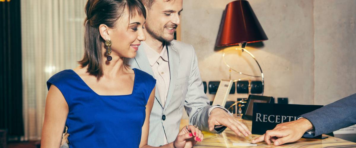 Couple doing the check-in at a luxury hotel paying by credit card