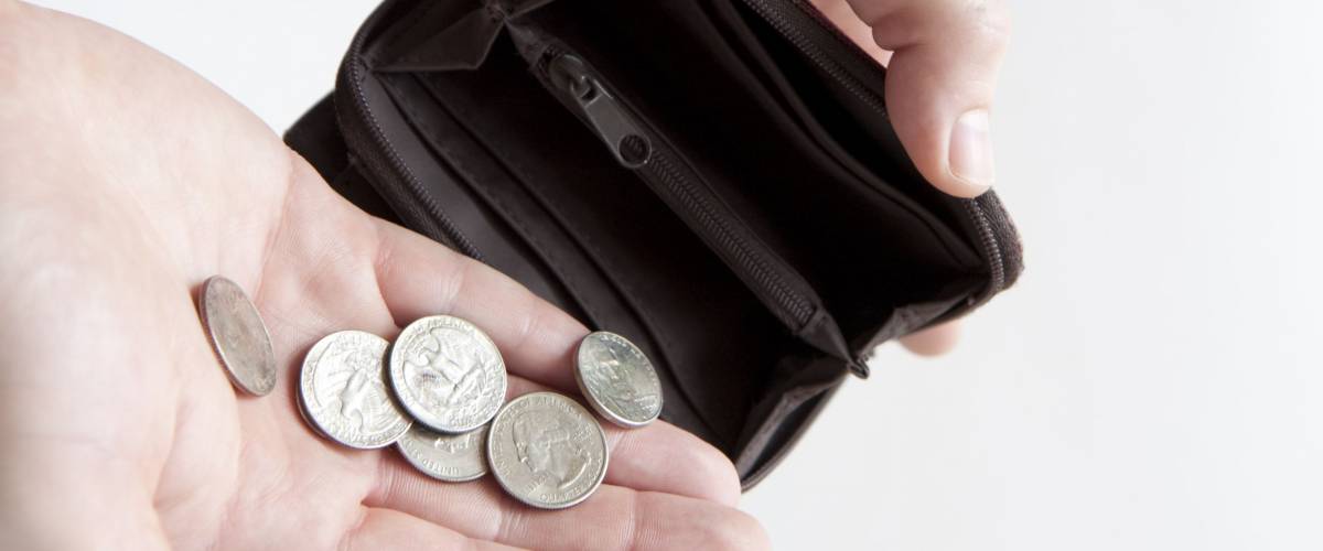 Man pouring coins into empty wallet