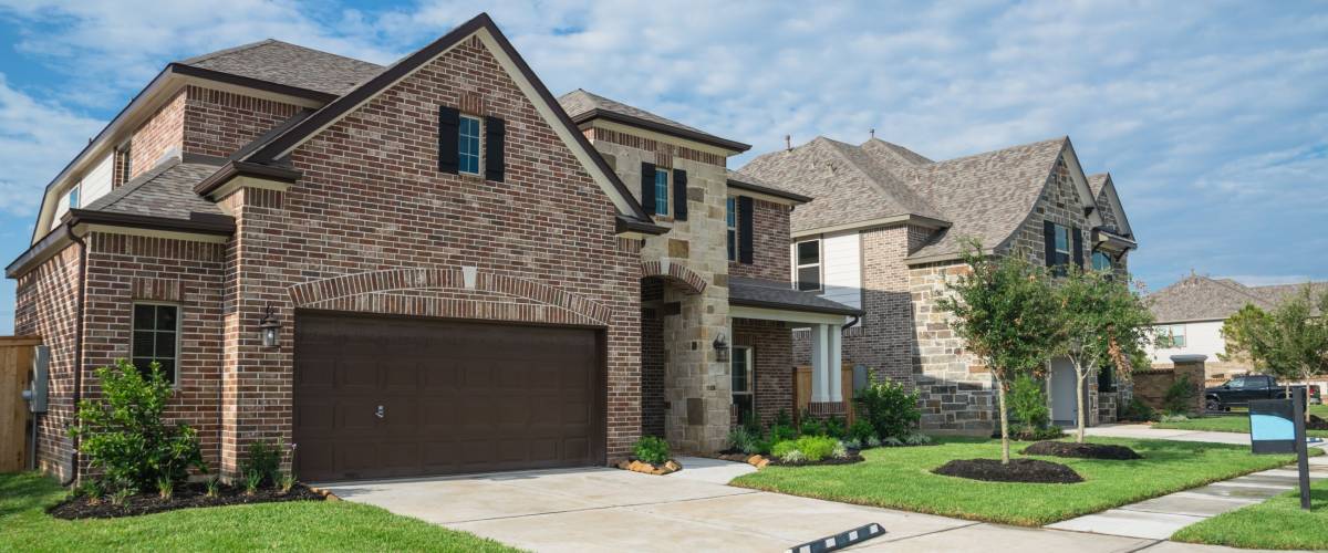Suburban American neighborhood street with row of brand new two story residential houses in Humble, Texas, US. Newly constructed, freshly built modern home with landscaped yard.